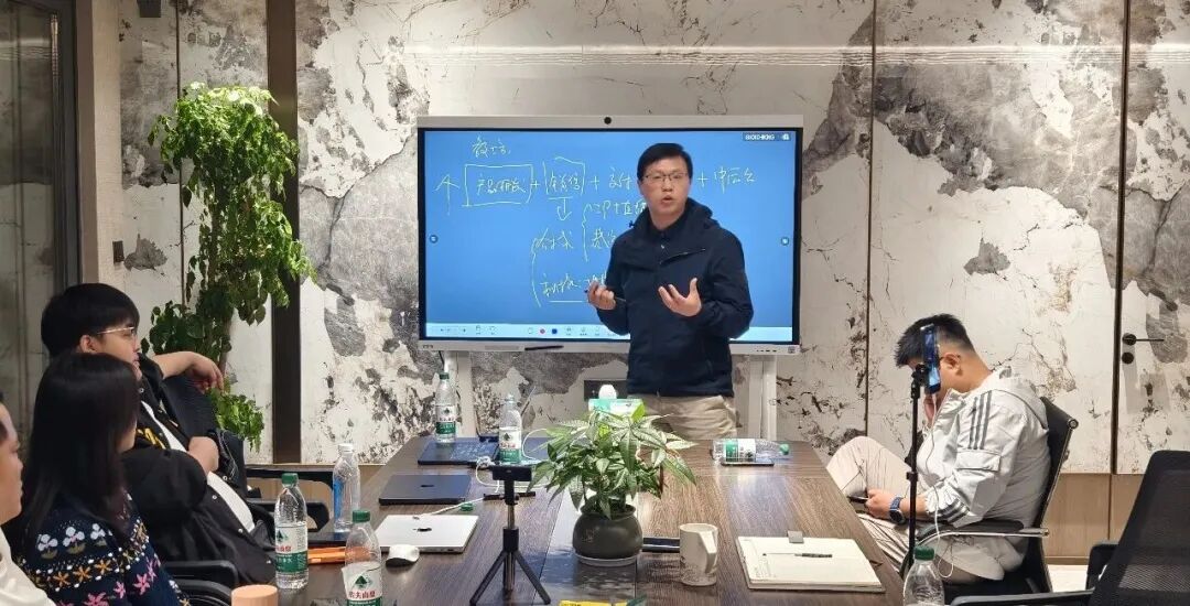 分享者在白板前讲解，参与者围桌听讲